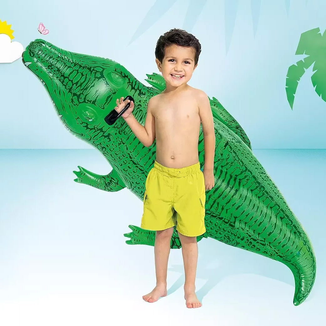 En esta fotografía se ve a un niño sosteniendo el Cocodrilo inflable INTEX de referencia 58546, con dimensiones 168 x 86 cm, color verde. El niño esta posando para una sesión de fotos.