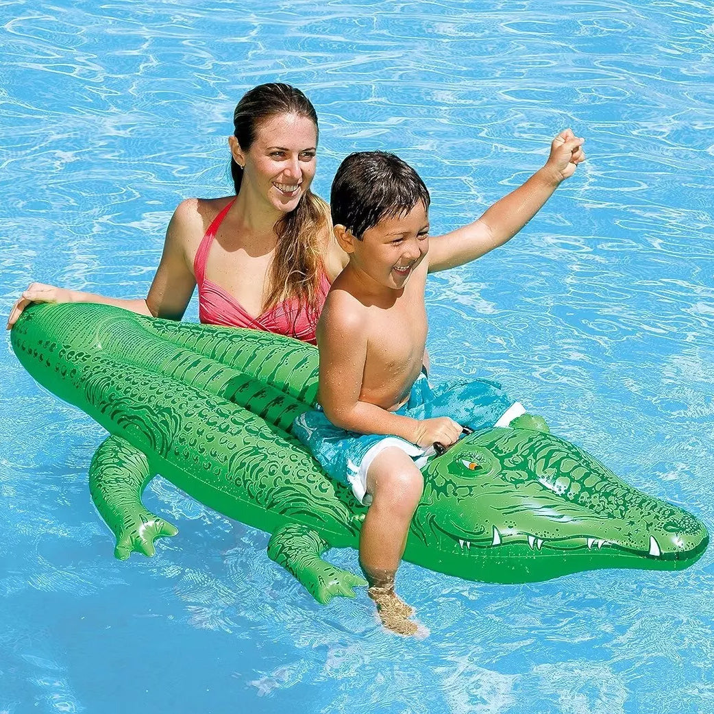 Cocodrilo inflable INTEX de referencia 58546, con dimensiones 168 x 86 cm, color verde. Sobre el cocodrilo inflable se ve a un niño de 5 años aproximadamente, siendo empujado por una mujer. Ambos están en una piscina.